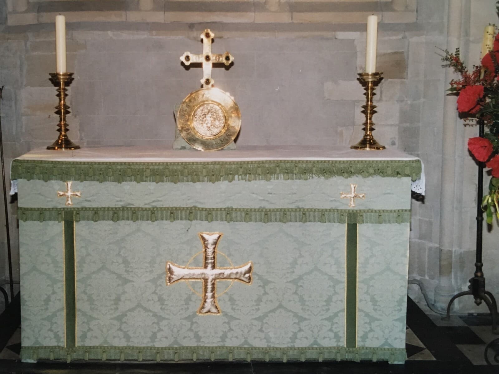 The altar at St James dressed in the pale green frontal with a white and gold cross, flanked by brass candlesticks