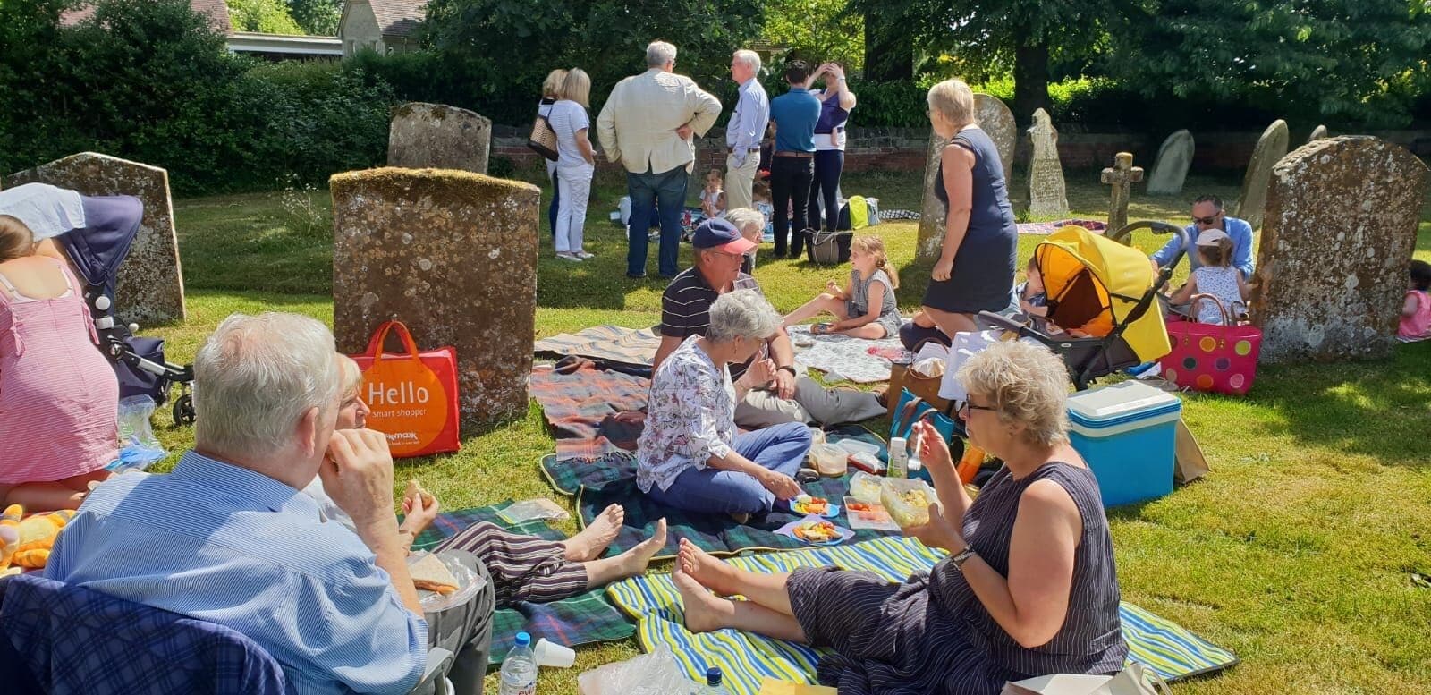 Parishioners gathered for a summer picnic on rugs among the gravestones