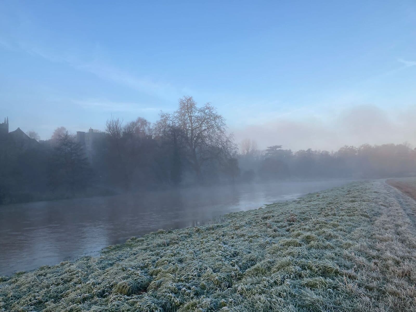 A frosty winter dawn over the River Avon, mist rising from the water below the church